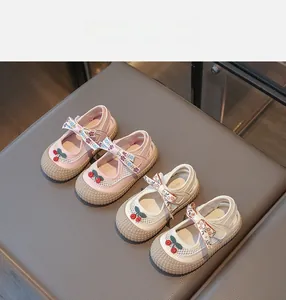 Vue détaillée de chaussures pour enfants rose et beige avec cerises et rubans à nœuds