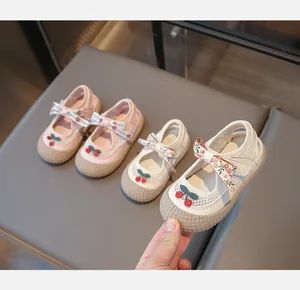 Détail de sandales fille avec maille, motifs cerise et nœuds fleuris à fermeture scratch