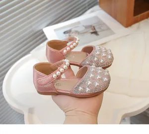Dettaglio dei sandali rosa con cinturini di perle e decorazione a cuore di strass