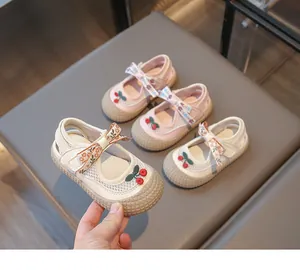 Détail de chaussures en maille pour enfant avec nœud floral et cerise rouge