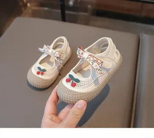 Détail de chaussures enfants avec maille respirante, nœud cerise et semelle antidérapante