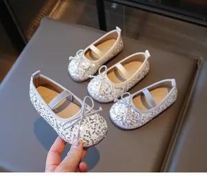 Detail showing silver sequin Mary Jane shoes with delicate bow and elastic strap