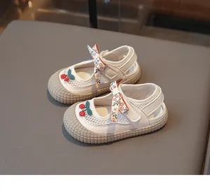 Détail de chaussures en maille pour fillettes avec broderie cerise et nœud floral