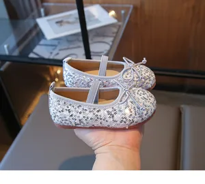 Close-up of silver sequin ballet flats with bow detail and elastic strap for girls