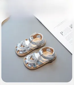 Détail de sandales argentées pour filles avec cœur en paillettes et bride velcro
