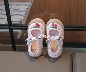 Détail de chaussures en maille rose pour filles avec cerises et nœud floral soyeux