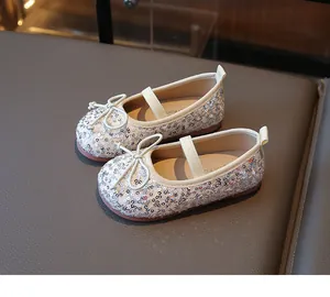 Detailed top view of sequined ballet flats with bow and elastic strap for kids