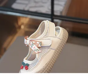 Détail de sandales en mesh pour enfants avec nœud floral, broderie cerise et semelle