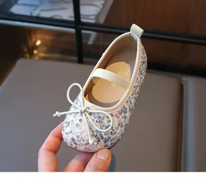 Detail of silver sequin ballet flats with bow accent and elastic strap for girls