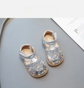 Gros plan de sandales argentées pour bébés avec motifs de cœur et strass scintillants