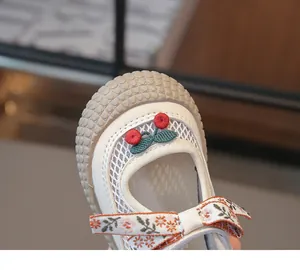 Détail de chaussures en résille pour enfants avec broderie cerise et nœud floral