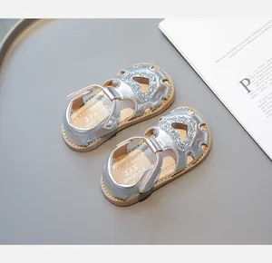 Détail de sandales argentées pour enfants avec paillettes en cœur et bride velcro