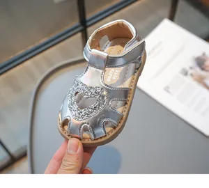 Détail de l'élégant cœur pailleté argenté et de la sangle velcro sur la sandale fille