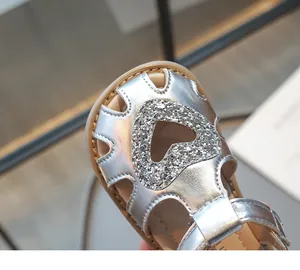 Détail de sandales argentées pour fille avec cœur à paillettes et bout fermé pour l'été