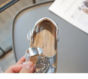 Détail de sandales argentées pour filles avec motif cœur pailleté et fermeture velcro