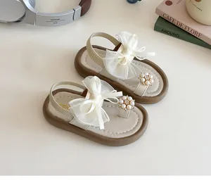 Detail of girls' cream sandals featuring a large organza bow and pearl flower decoration