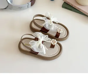 Detail of girls' thong sandals featuring large mesh bows and pearl floral accents