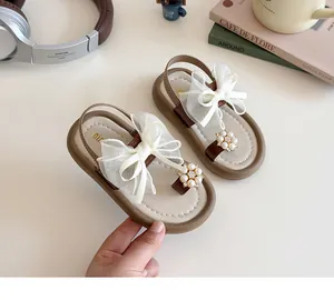 Detail of girls' sandals with cream bow, pearl flower accent and golden logo insole