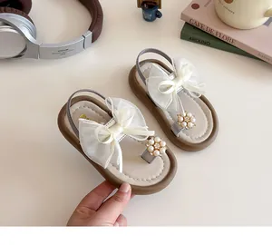 Detail of girls' sandals featuring white mesh bow, pearl flower, and elastic heel strap