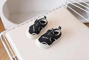 Détail de sandales de sport enfant avec empeigne noire et semelle blanche épaisse