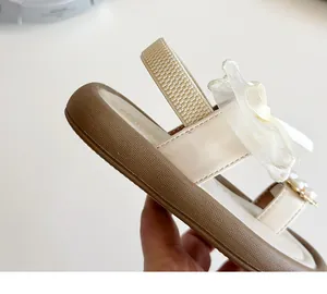 Macro shot of girls' beige sandals featuring mesh bow and elegant pearl details