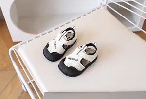 Gros plan de sandales pour bébés avec protection d'orteils noire et scratchs blancs