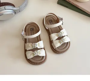 Detail van strass-vlinderdas en antislip rubberen zool op sandalen voor meisjes