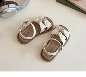 Detail van beige meisjessandalen met zijden strik, strassteentjes en zachte rubberen zool