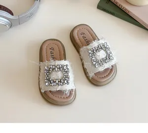 Detalle de sandalias crema para niña con hebilla de strass y bordes de flecos