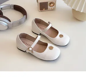 Dettaglio scarpe Mary Jane bianche per bambina con camelia dorata e ciondolo di perle