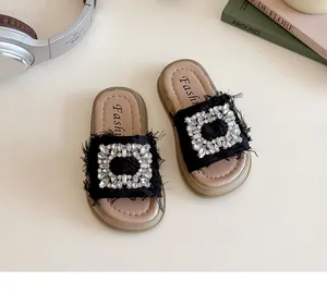 Detalle de sandalias negras con plataforma para niña con hebilla de strass y bordes deshilachados