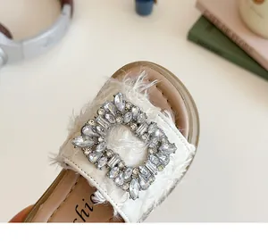 Detalle macro de sandalias infantiles con tejido crema y hebilla de diamantes de imitación