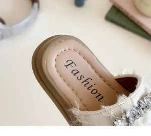 Detalle de sandalias de lona beige para niñas con diamantes de imitación y flecos