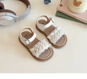 Dettaglio di sandali bianchi da bambina con pizzo delicato e decorazioni in perline