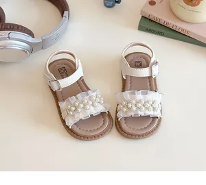 Dettaglio di sandali bianchi da bambina con pizzo delicato e decorazioni di perle
