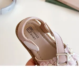 Dettaglio di sandali rosa per bambine con petali di perle e cinturino con velcro