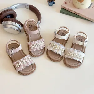 Sandali da bambina rosa e beige con perle e pizzi su uno sfondo decorativo da scrivania