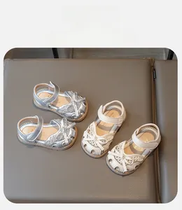 Close-up of silver and beige closed-toe toddler sandals with bow and lace cutouts