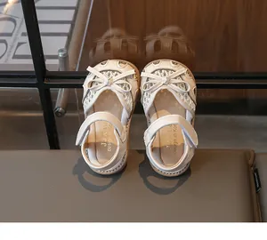 Close-up of cream girls' sandals featuring lace mesh, bow detail, and velcro strap design