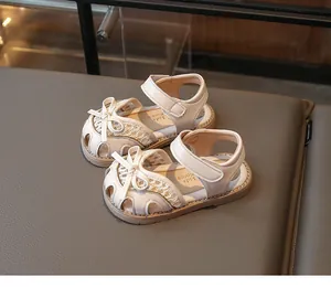 Close-up of cream kids closed-toe sandals featuring a bow decoration and velcro strap
