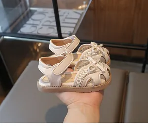 Detail of cream girls' princess sandals featuring a bow decoration and velcro strap