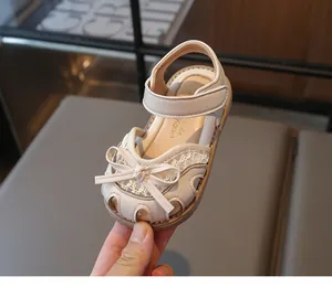 Detail of toddler girls' cream sandals featuring lace embroidery and a bow knot closure