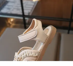 Close-up of girls beige sandals featuring hook-and-loop straps and elegant lace mesh details