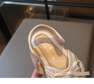 Detail of beige girls' princess sandals showing delicate white lace and bow accents