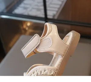Detail of girls' cream sandal featuring white lace mesh and adjustable hook-and-loop strap