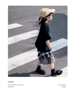 Kids black double-strap sandals styled with casual summer outfit on a zebra crossing
