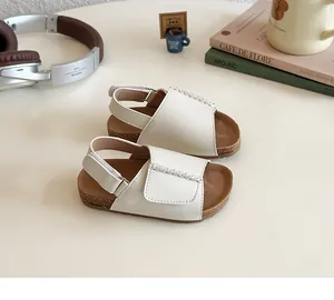 Detail von cremefarbenen Kinder-Sandalen mit gewebter Textur und Kork-Zwischensohle