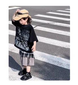 Outdoor street style view of boy's black oversized tee and grey side-striped shorts