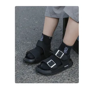 Close-up of black double-strap sandals for kids featuring thick soles and silver buckles