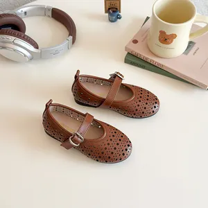 Detail of dark brown girls' Mary Jane shoes with hollow patterns and heart-shaped buckle